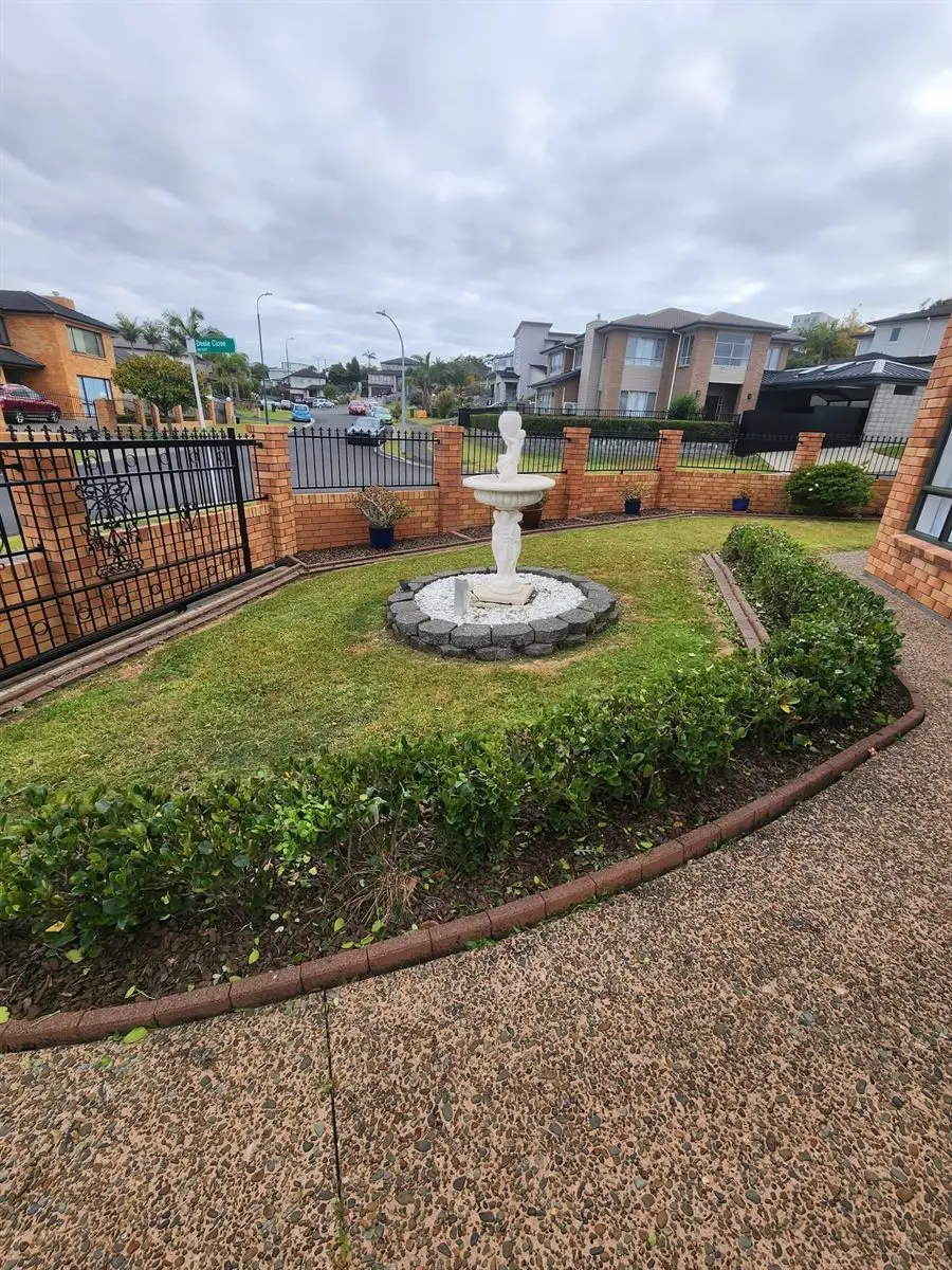 Neatly mown front lawn with trimmed hedges around a garden fountain, North Shore Auckland